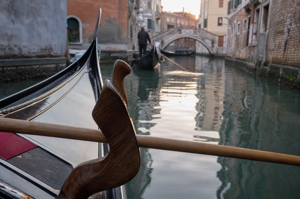The forcola, the carved wooden oarlock of a gondola, in close view with the long wooden oar resting in its curve
